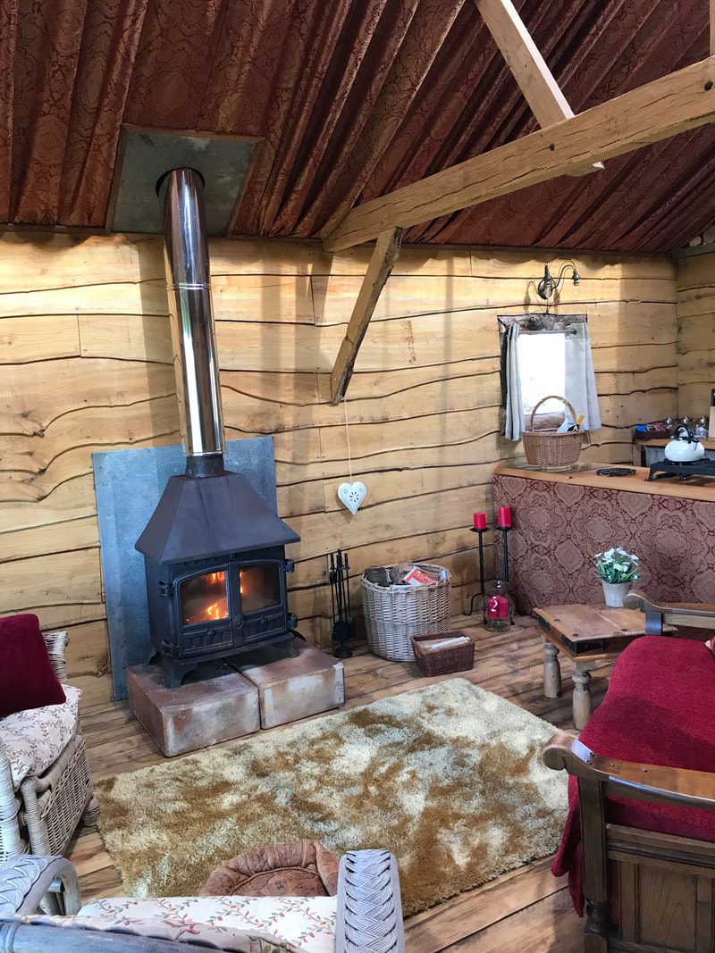 Wood burning stove and comfortable seating at Daisy Cabin Picture